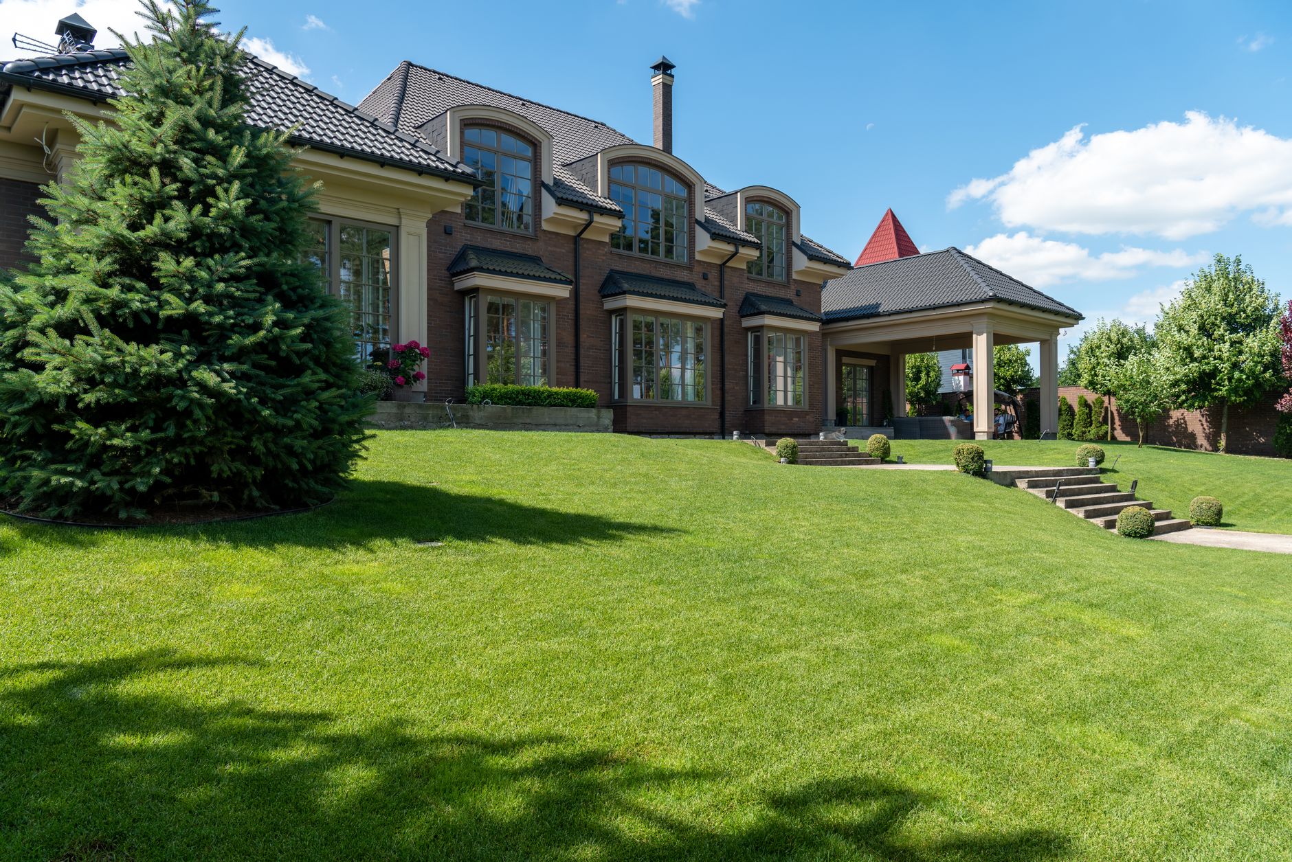 Large house with a wide, freshly cut front lawn under a blue sky