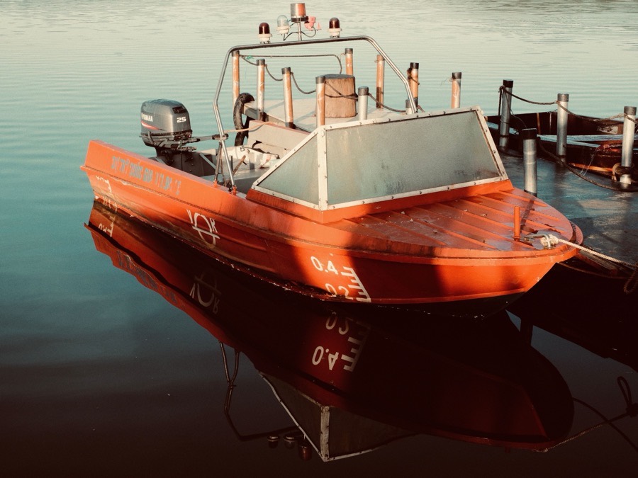 A moored motorboat lying alongside a timber jetty on flat water