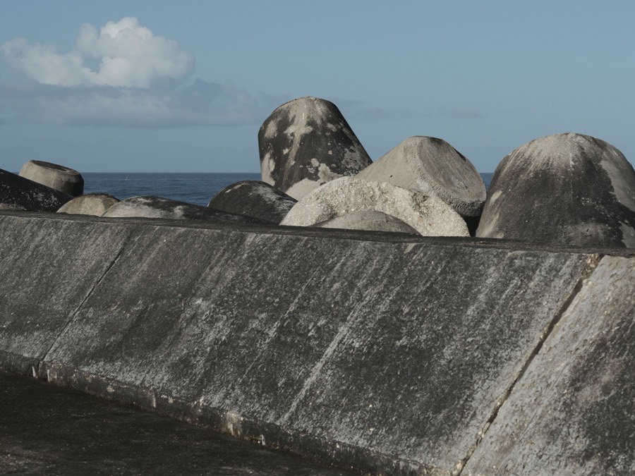 A stone-faced seawall holding a bank against calm open water