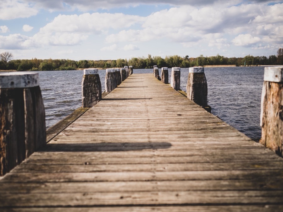 A timber walkway running from the bank out over open water to a pier head