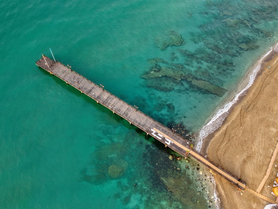 A jetty running out into clear water, seen from directly above
