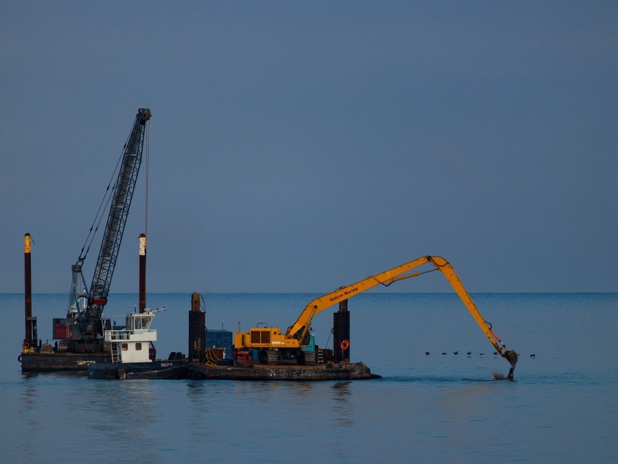 A crane barge working out on open water under a clear sky