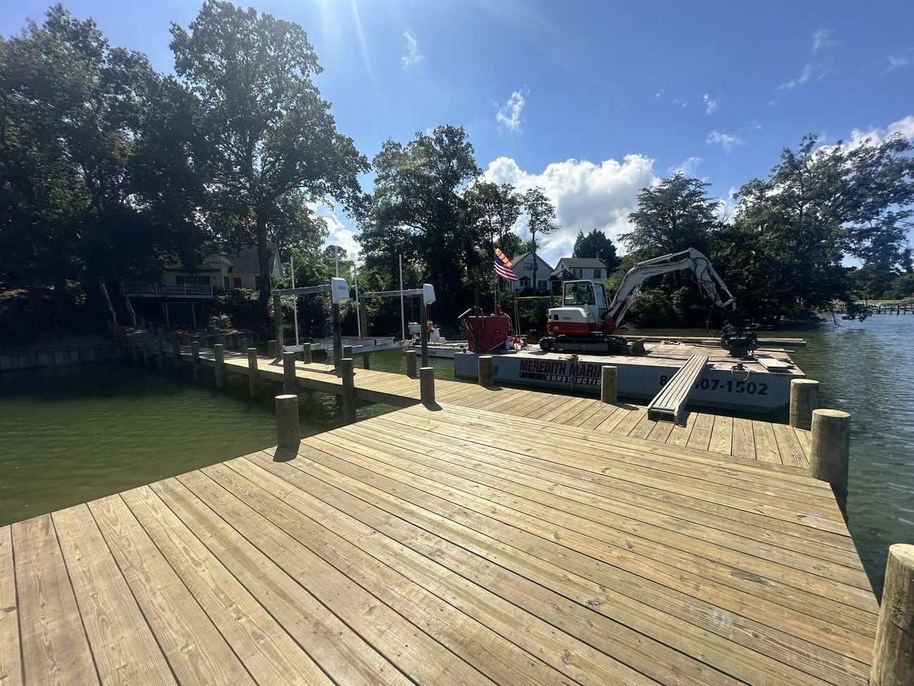 The Meredith Marine work barge with its red excavator tied alongside a large new timber dock