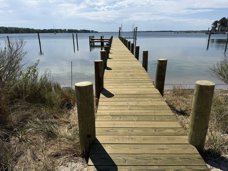 A new pressure-treated timber walkway running from the bank straight out over open water to a pier head