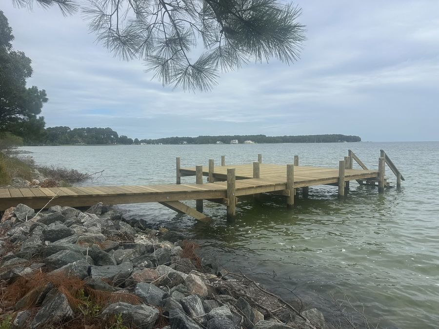 Heavy granite riprap armouring a shoreline in front of a timber pier and finger dock