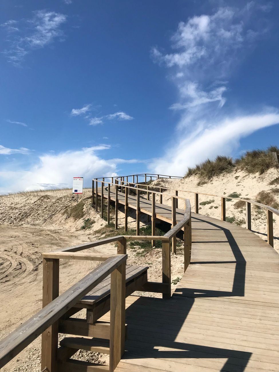 Timber steps and walkway climbing over a dune toward the beach