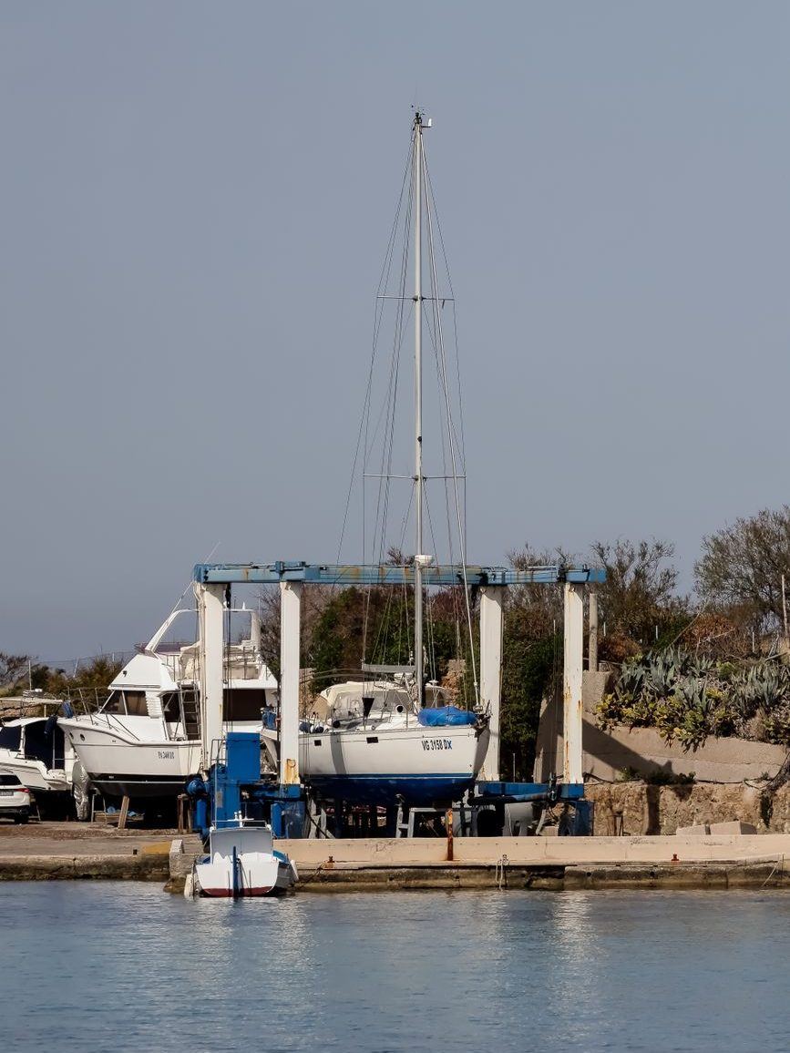 Sailboat tied alongside a low timber dock on calm water