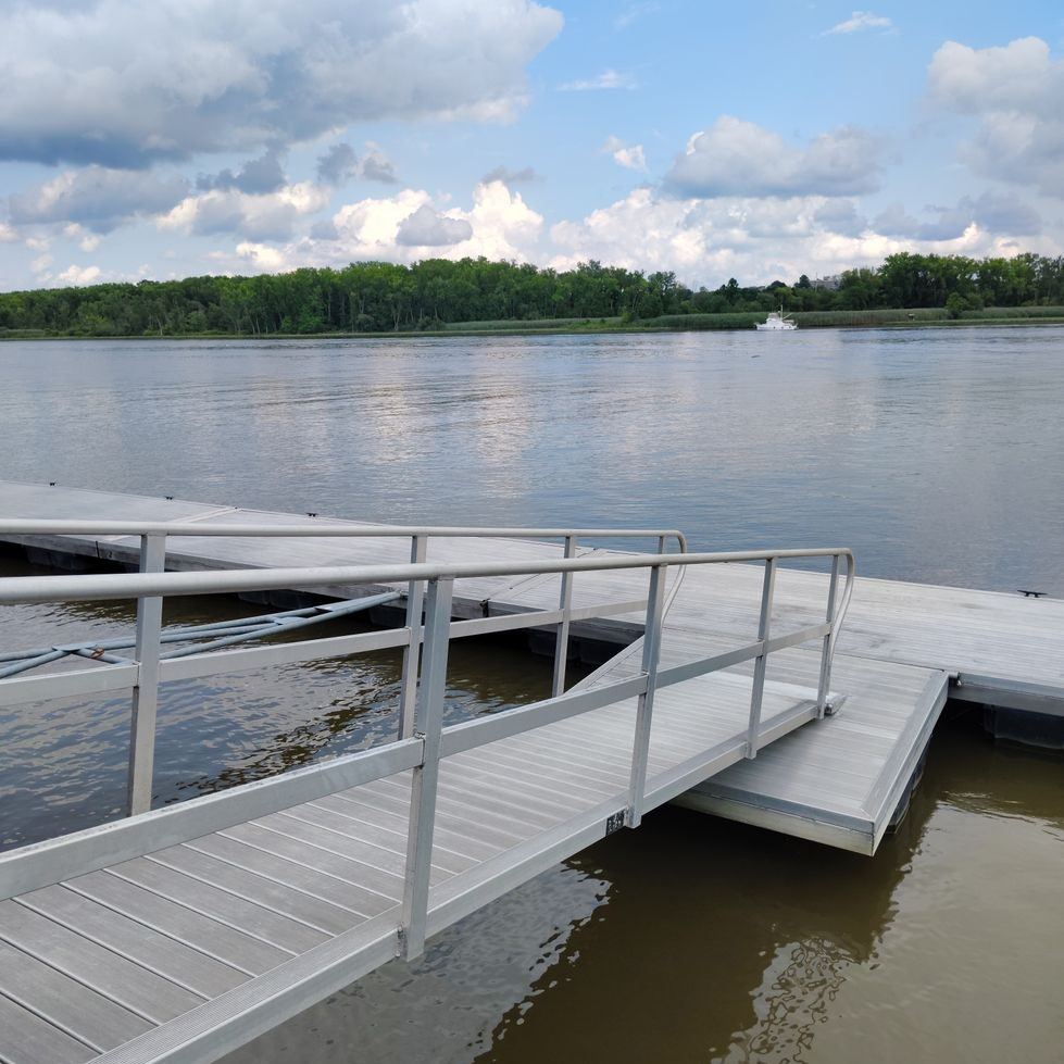 Aluminum gangway hinged from the bank down to a floating dock on the water