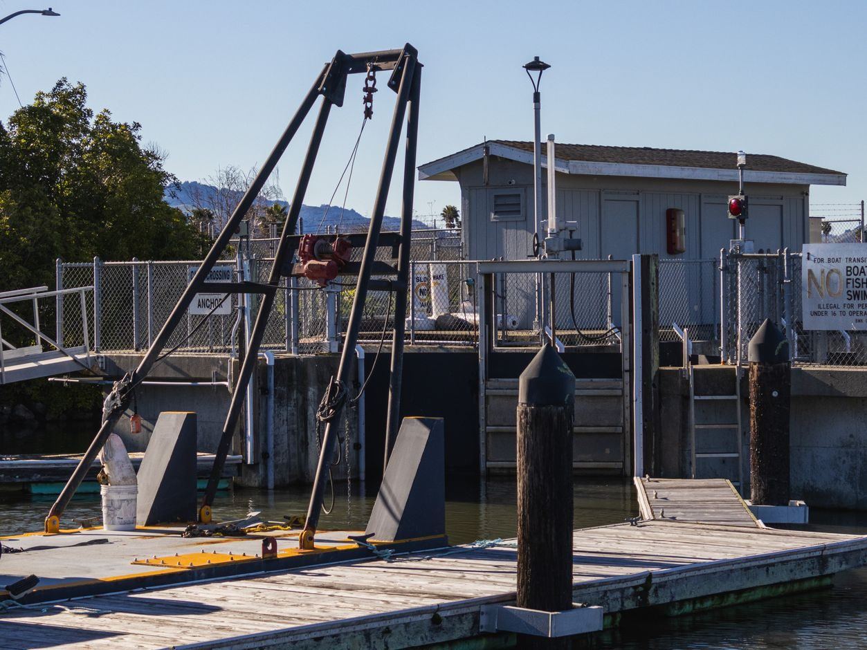 Boat lift and davit rig mounted on a floating dock at the water's edge