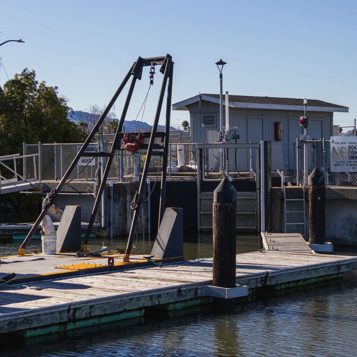 Boat lift and davit rig mounted on a floating dock at the water's edge