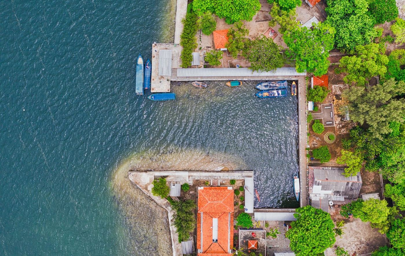 Aerial view of a waterfront home with a private dock reaching out over clear shallow water