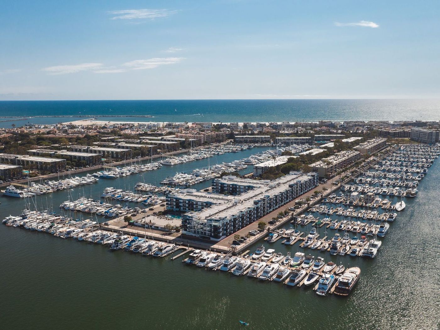 Aerial view of a marina basin lined with docks and moored boats beside the coast