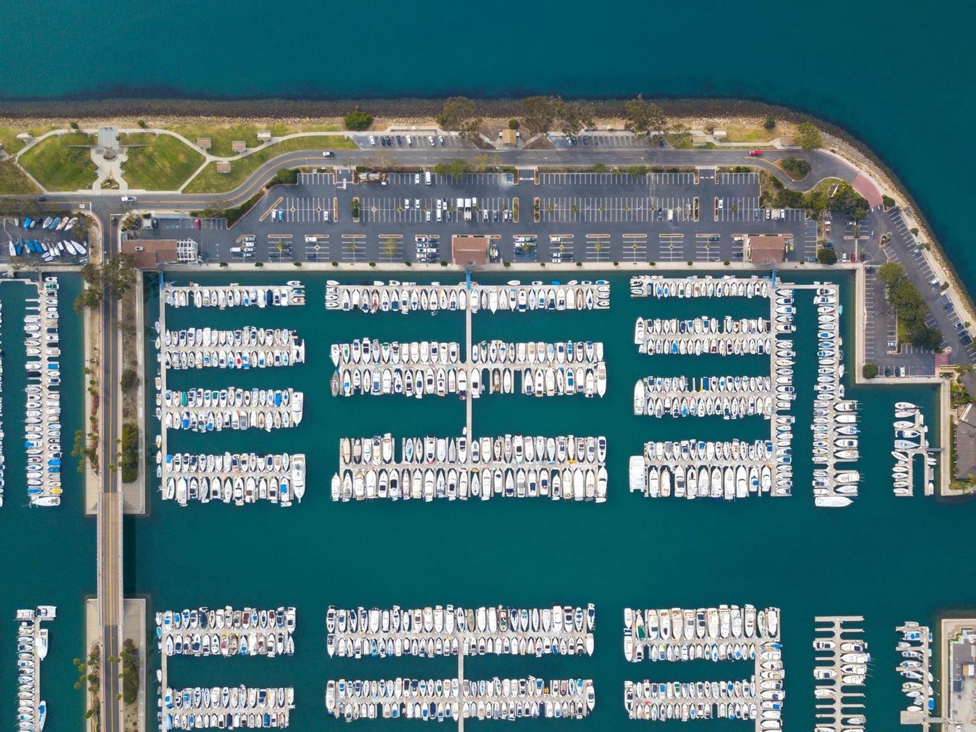 Aerial view of a large marina, its docks arranged in long parallel rows beside a car park