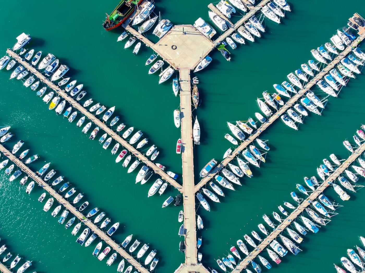 Straight-down aerial of finger docks radiating from a central pier with boats in every slip