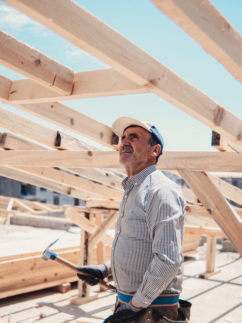 Carpenter standing under the new timber frame of a structure he is building