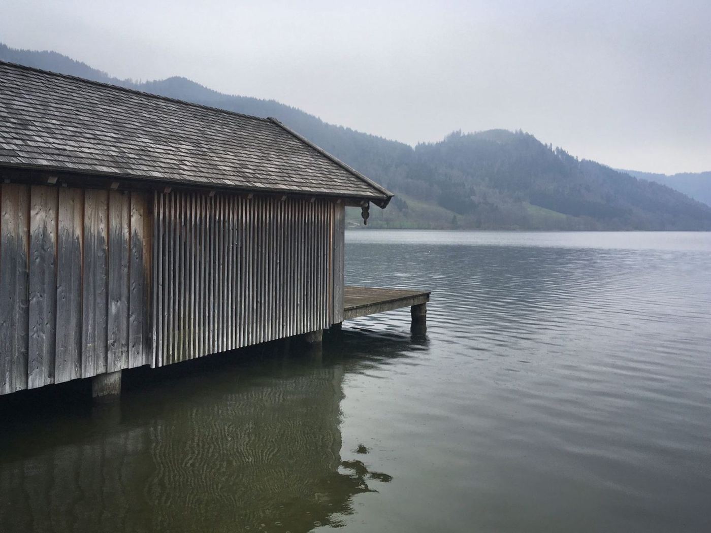 Long timber boathouse standing over calm water with a landing at its far end