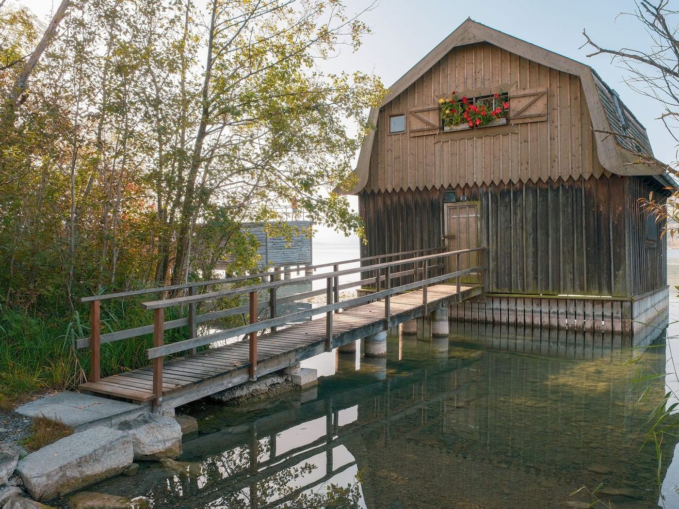 Timber boathouse on pilings with a walkway running out to it across the shallows
