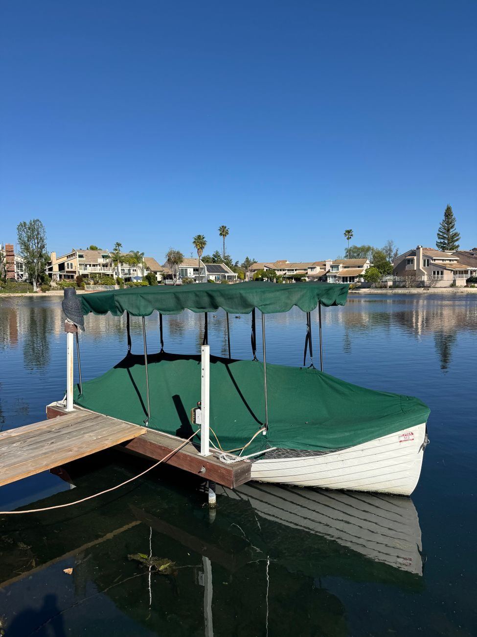 Small covered boat slip with a canopy over a moored boat on a still lake