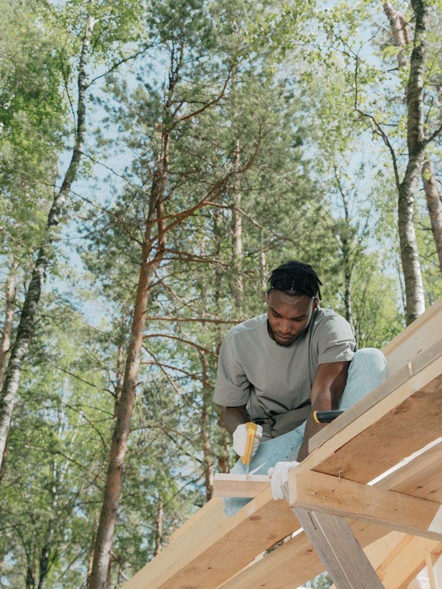 Worker kneeling to fix decking boards on a build among the trees