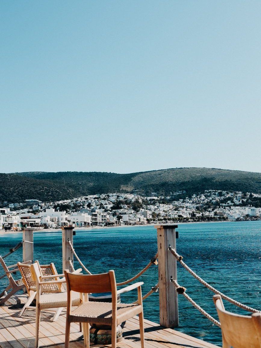 Timber deck with chairs and a rope railing set out over bright turquoise water