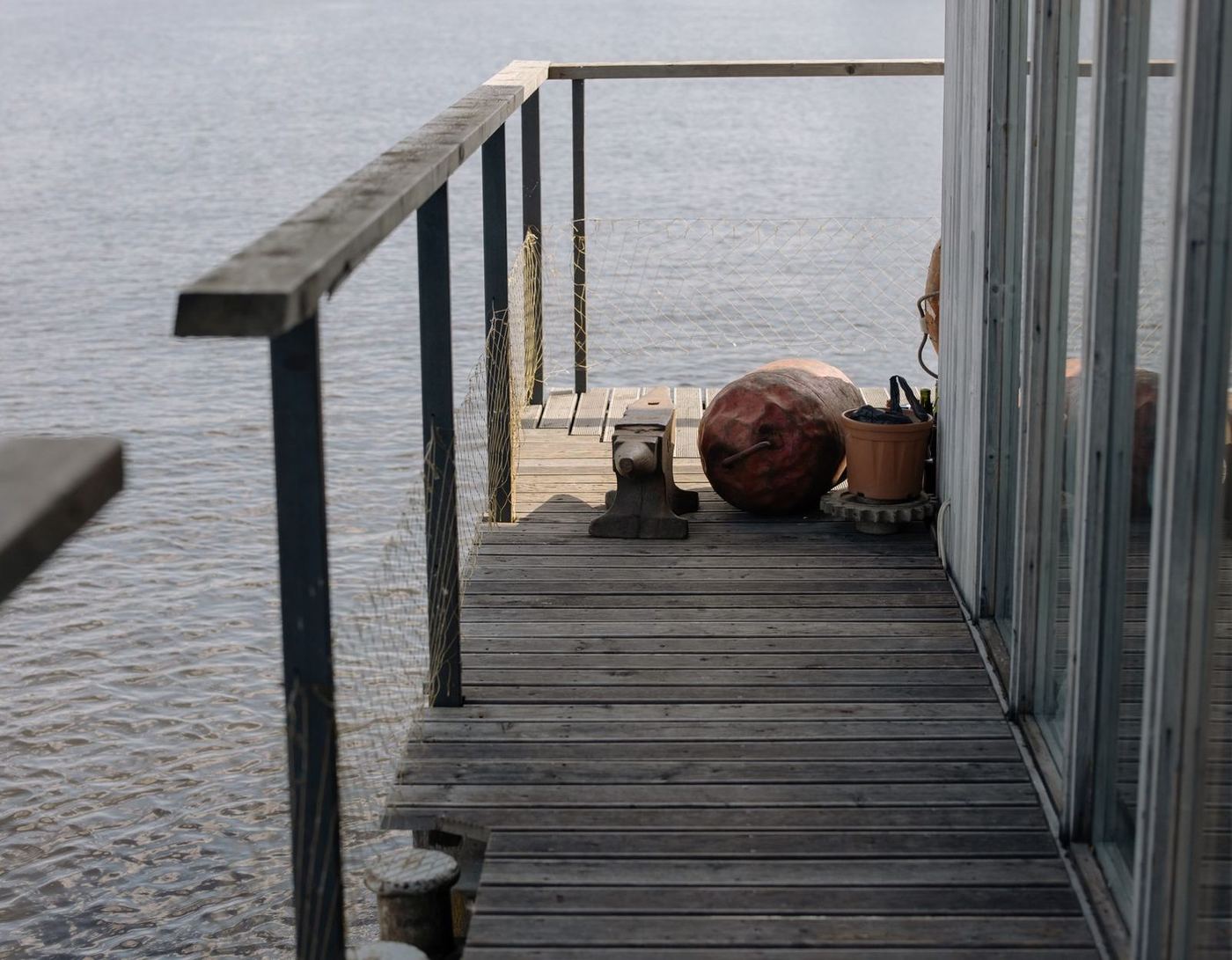 Timber dock walkway with a rail running along the water beside a boat shed