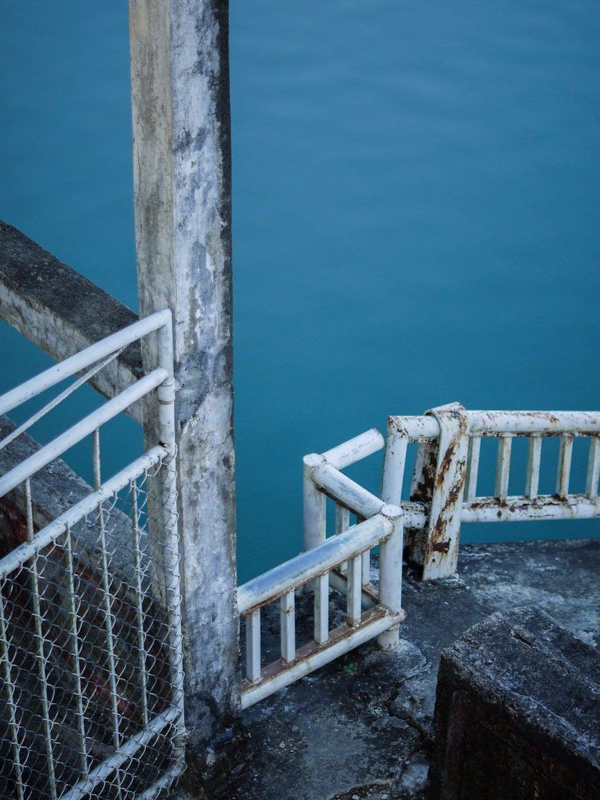 Steel handrail and steps running down off a dock into deep blue water