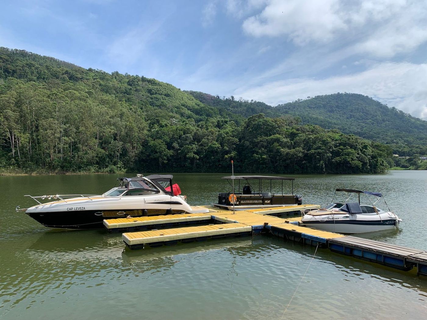Floating dock with boats moored either side, hills rising behind the far shore