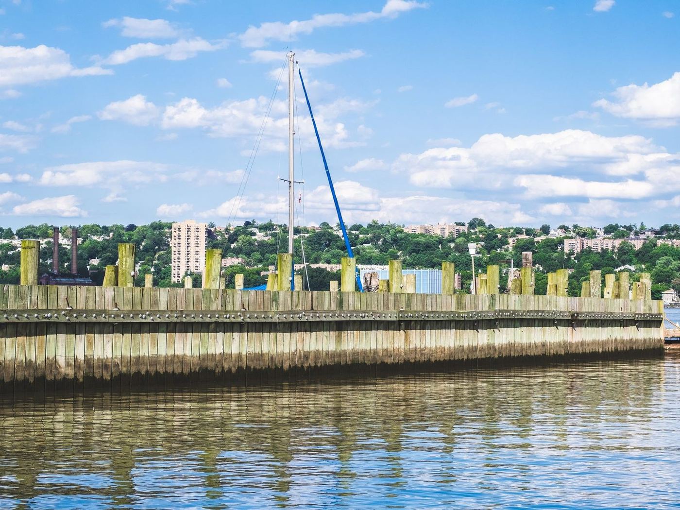 Long timber sheet-pile seawall running along the waterfront with the town rising behind